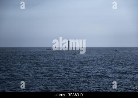 Minimalist seacape with soft dark tones and distant lighthouse silhouette on the horizon. Calm and atmospheric composition symbolizing peace. Stock Photo