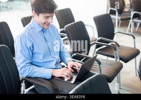Confident businessman using laptop in empty conference room Stock Photo
