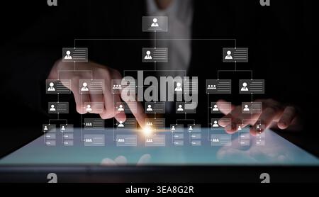 A business professional interacts with a digital tablet displaying an organizational chart. The focus is on user icons and data flow, emphasizing Stock Photo