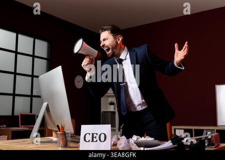 Angry businessman shouting into megaphone in office Stock Photo