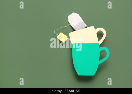 Tea bag with yellow label and paper cups on green background Stock Photo