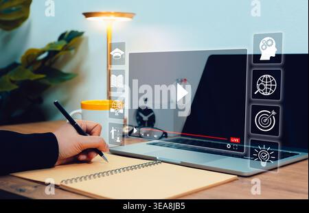 Digital education concept. Person taking notes while watching live online webinar on laptop, with icons for learning, certification, knowledge, skills Stock Photo
