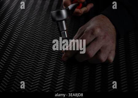 Close up of hand positioning socket on bolt using ratchet wrench with extension over dark textured background. Mechanical fastening step in repair or Stock Photo