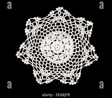 Vintage handmade white ornate crochet doily isolated cutout on black background. Delicate lace pattern textile ideal for design, overlay, and composit Stock Photo