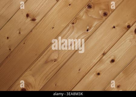 Wooden planks lay at an angle, showing the natural grain and knots. The color is light and warm, suggesting a cozy and rustic setting. This type of wo Stock Photo