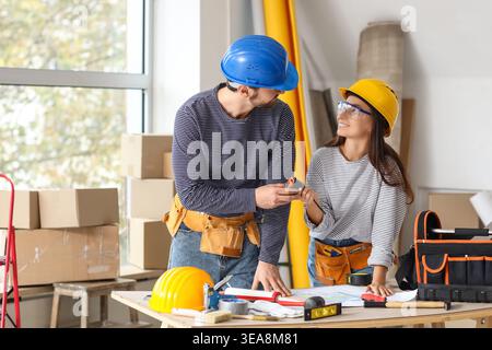 Young couple with tape measure at table during repair in their new house Stock Photo