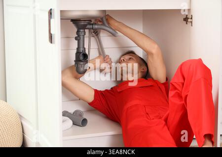 Male plumber fixing sink in kitchen Stock Photo