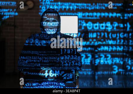 Hacker and projection of programming code in dark room Stock Photo