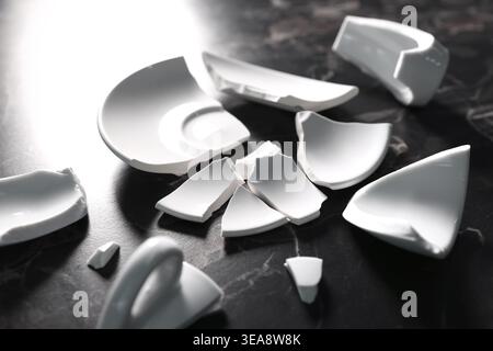 Pieces of broken saucer and cup on black table, closeup Stock Photo