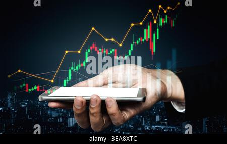 A businessman holds a smartphone displaying financial graphs and stock market data on a dark city backdrop, symbolizing growth and technological Stock Photo