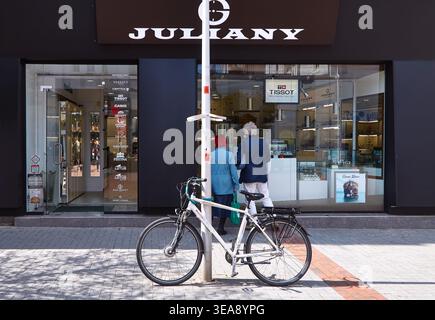 Varna, Bulgaria - April 20, 2026: Bicycle secured to a pole on the sidewalk outside Julianny store with Tissot watches visible in the display window Stock Photo