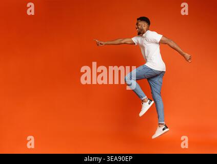 Excited african-american man jumping on orange background Stock Photo
