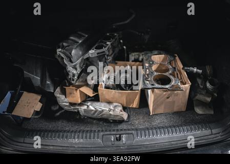 A collection of car parts including an intake manifold, head gasket, and other components are packed inside a car's trunk. The scene captures the tool Stock Photo