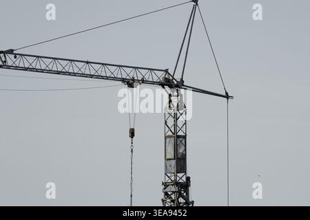 Close view of a tower crane at a construction site against a clear sky. Industrial infrastructure and building development concept. Stock Photo