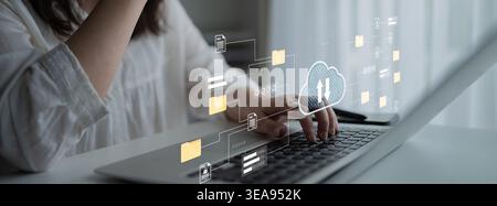 A woman engages with a laptop while cloud technology graphics illustrate digital communication and data management, showcasing modern work dynamics Stock Photo