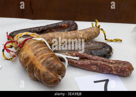 Assorted cured sausages on white surface with rustic presentation Stock Photo