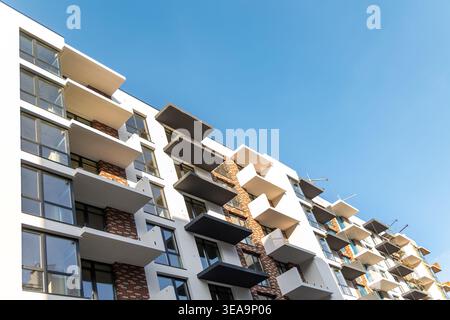 Modern Apartment Building With Balconies and Blue Sky. Low angle view of a contemporary residential apartment building with repeating balconies, large Stock Photo