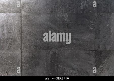 Dark Stone Tile Surface Texture Background. Close-up of dark gray stone tiles with natural texture and clean grout lines, ideal for interior design Stock Photo