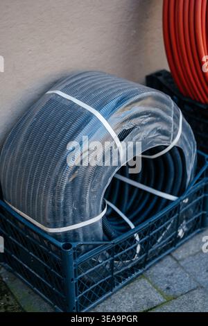 Worker Organizing PVC Corrugated Conduit Rolls Against Concrete Wall In Workshop Environment Stock Photo
