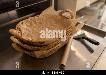 Empty wicker basket with parchment paper on bakery counter, preparation for fresh bread display, copy space Stock Photo
