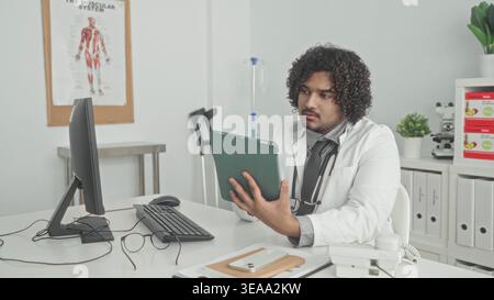 Man holds tablet with right hand and uses mouse with left hand, stethoscope on neck, in medical building; focused care. Stock Photo