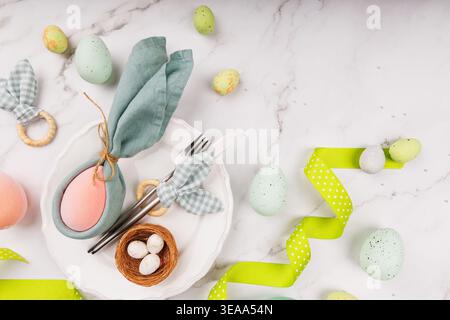 Pastel Easter Setting with Eggs, Napkin Bunny and Ribbon Stock Photo