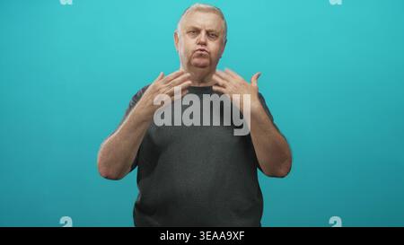 Man gesturing with hands in a studio against a teal backdrop, mid signing and mouth forming shapes; contemplation communication. Stock Photo