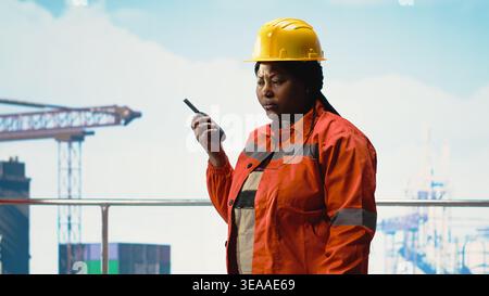 Drilling barge engineers use two way radio to communicate with logistics crew, monitoring systems. Offshore platform team talking in walkie talkie, controlling operation Stock Photo