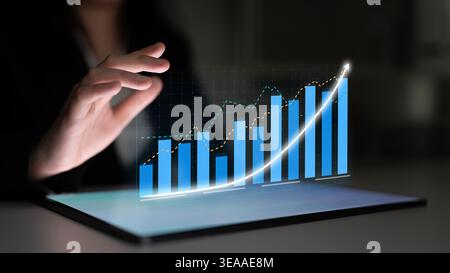 A person interacts with a transparent display showcasing growth trends and data analysis, highlighting innovation and technology in a corporate Stock Photo