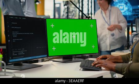 Green screen computer used by admin in office doing software development to launch new features. Mockup PC used by woman in startup company writing computer programs, doing code, camera B Stock Photo