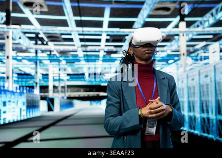Data center admin using VR goggles to implement power management solutions reducing energy consumption. Server farm IT specialist refining algorithms for faster processing using virtual reality tech Stock Photo