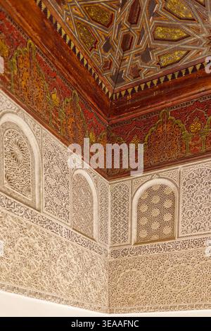 311 Carved-painted cedar wood ceiling, lavishly sculpted stucco wall, corner of the Ben Youssef Madrasa courtyard doorway vestibule. Marrakesh-Morocco Stock Photo