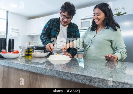 Young couple joyfully cooking and preparing homemade dough together Stock Photo
