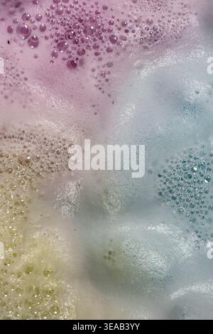 Colorful foam and bubbles produced by bath bombs in water, creates an organic, textured background element resembling a nebula scene from outer space. Stock Photo