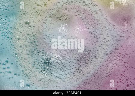 Colorful foam and bubbles produced by bath bombs in water, creates an organic, textured background element resembling a nebula scene from outer space. Stock Photo