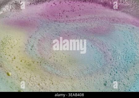 Colorful foam and bubbles produced by bath bombs in water, creates an organic, textured background element resembling a nebula scene from outer space. Stock Photo