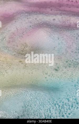 Colorful foam and bubbles produced by bath bombs in water, creates an organic, textured background element resembling a nebula scene from outer space. Stock Photo
