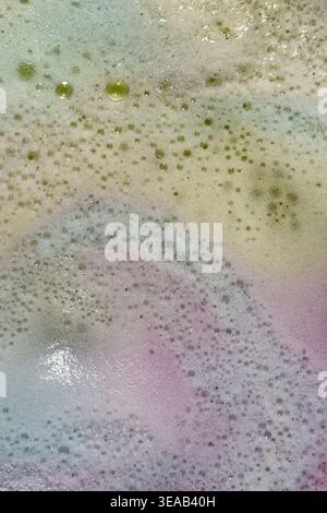 Colorful foam and bubbles produced by bath bombs in water, creates an organic, textured background element resembling a nebula scene from outer space. Stock Photo