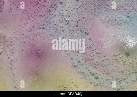 Colorful foam and bubbles produced by bath bombs in water, creates an organic, textured background element resembling a nebula scene from outer space. Stock Photo