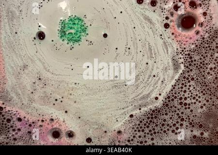 Colorful foam and bubbles produced by bath bombs in water, creates an organic, textured background element resembling a nebula scene from outer space. Stock Photo