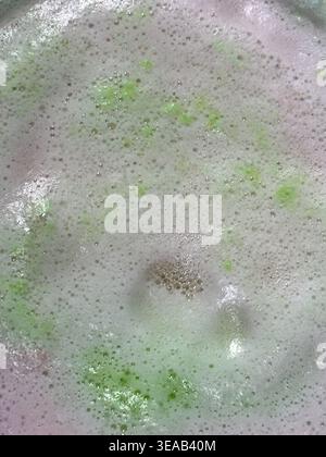 Colorful foam and bubbles produced by bath bombs in water, creates an organic, textured background element resembling a nebula scene from outer space. Stock Photo