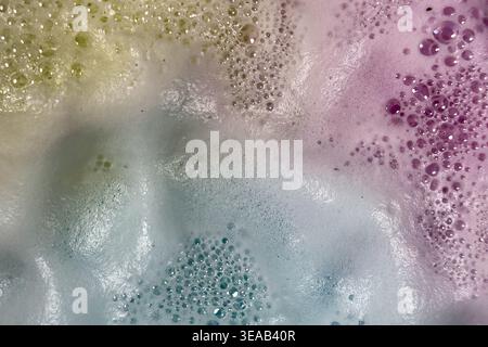 Colorful foam and bubbles produced by bath bombs in water, creates an organic, textured background element resembling a nebula scene from outer space. Stock Photo