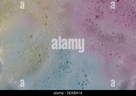 Colorful foam and bubbles produced by bath bombs in water, creates an organic, textured background element resembling a nebula scene from outer space. Stock Photo