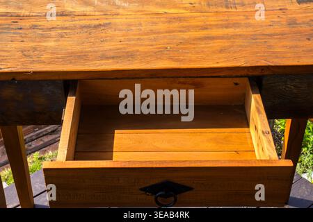 Rustic Wooden Desk with Open Drawer in Outdoor Setting, Brazil - High angle view of a handcrafted reclaimed wood table featuring an open empty drawer. Stock Photo