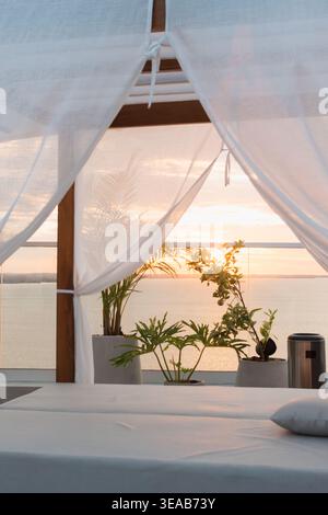Sunset Time Frame Sunset glows over calm waters near forested hills. Boats leave trails ...