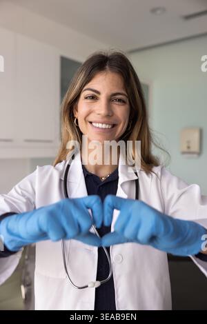 Cardiologist in white uniform forming heart symbol with her hands Stock Photo