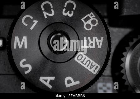 Macro closeup of camera mode dial with PASM settings and auto icons showing textured metal control and photography interface detail Stock Photo
