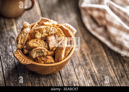 Warm almond biscotti cantuccini piled in a ceramic bowl beside a coffee cup on a rustic wooden table, evoking cozy morning vibes, homemade baking, and Stock Photo