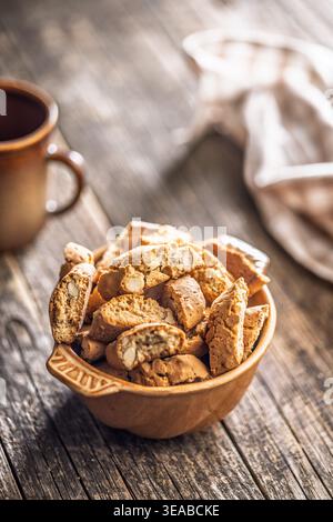 Warm almond biscotti cantuccini piled in a ceramic bowl beside a coffee cup on a rustic wooden table, evoking cozy morning vibes, homemade baking, and Stock Photo