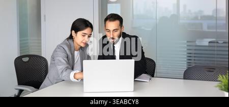 Multiethnic colleagues working together in office, reviewing information on laptop Stock Photo